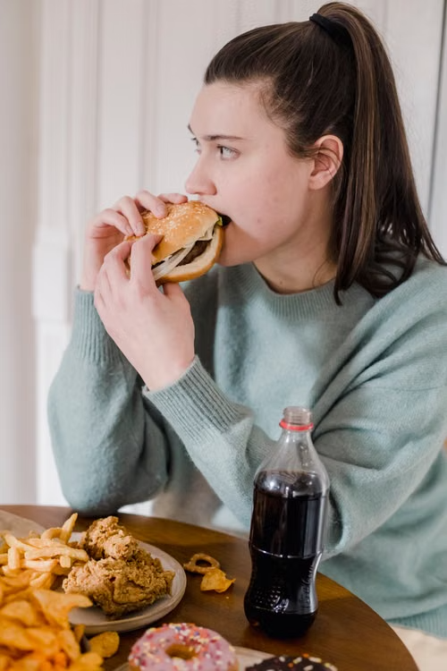 Mujer comiendo comida rápida y ultraprocesados