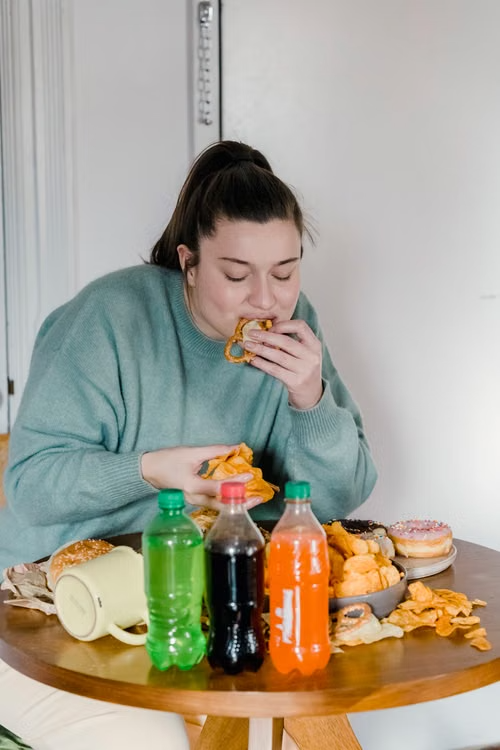 Mujer comiendo snacks, gaseosas y exceso de azúcar